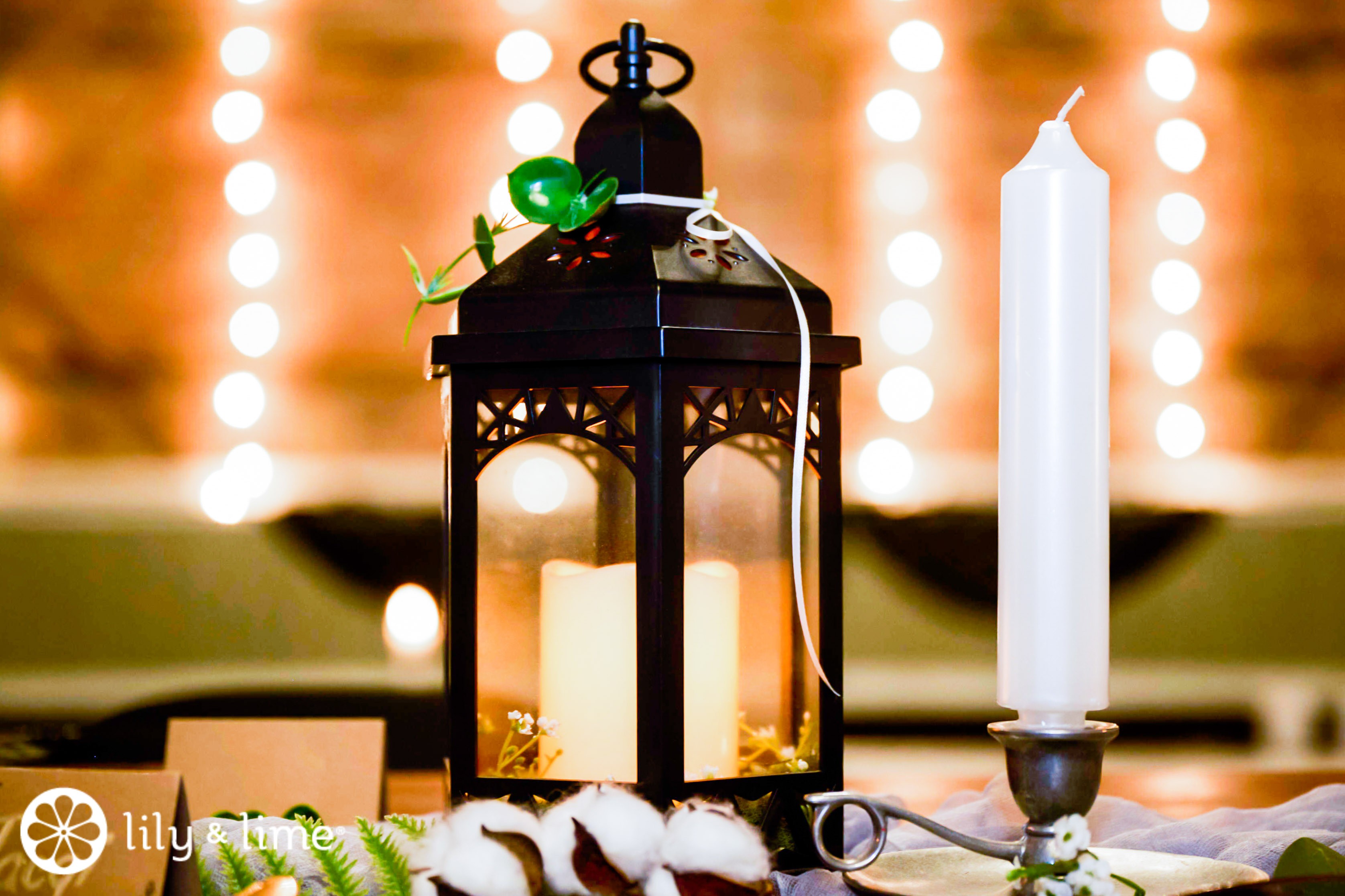 Reception table setting details - Black tablecloth, white candles, black  birdcage with white and green floral arrangement